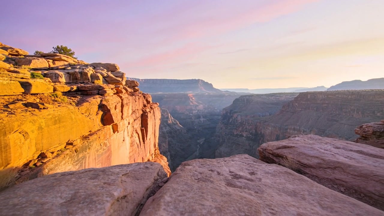 Pushing-in drone revealing sandstone ledge at canyon rim, highlighting layered cliff textures