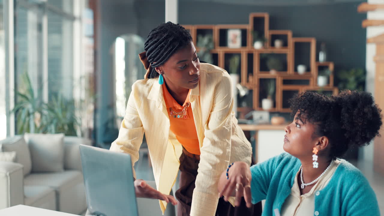 Due giovani donne afroamericane che collaborano e ridono in un ufficio moderno