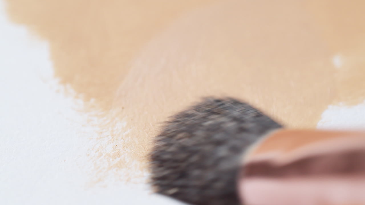 작은  ⁇ 질이 온 지역을  ⁇ 는  ⁇ 색 질감 표면에 갈색 물질을 적용하는 동안 부드러운 스트로크를 만드는 클로즈업 뷰