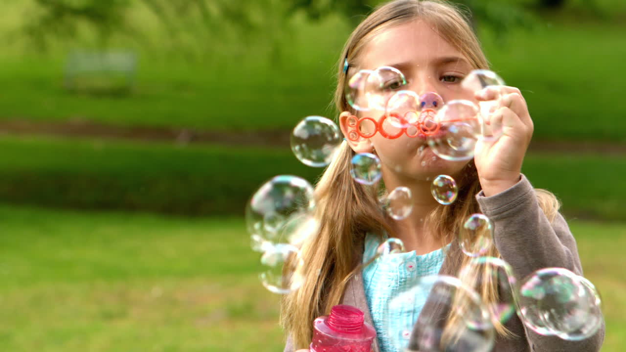 una niña soplando burbujas en el parque