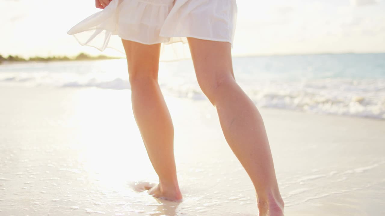Gambe di donna caucasica che cammina a piedi nudi sulla spiaggia