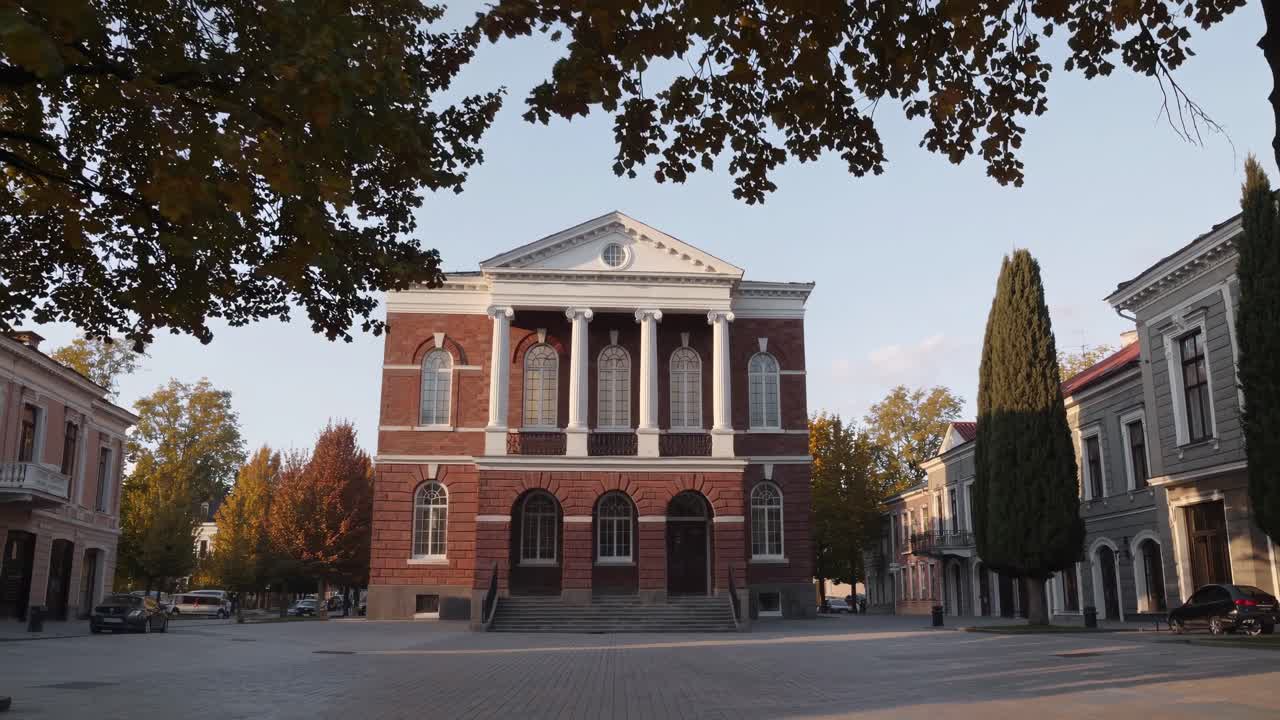 Autumn scene showcasing a historic building framed by vibrant trees, capturing the essence of seasonal change and architectural beauty in a tranquil urban setting