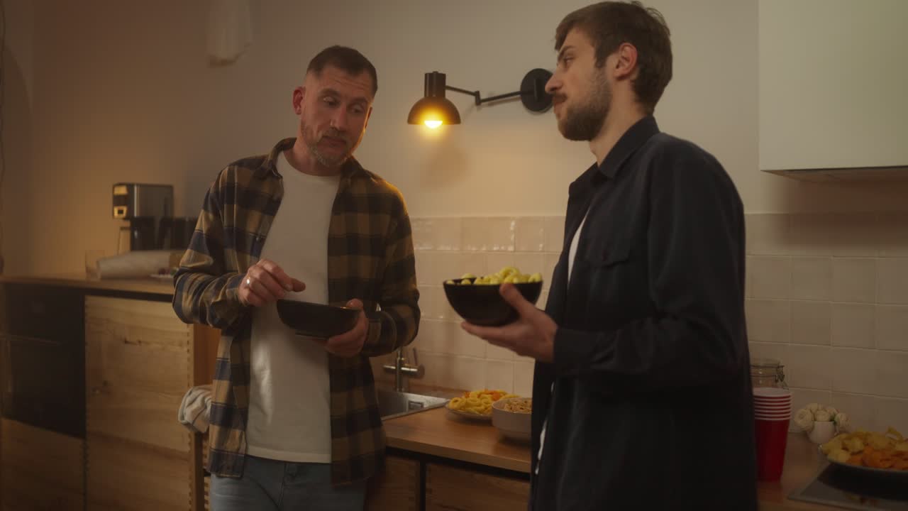 hombres hablando y comiendo bocadillos en una cocina