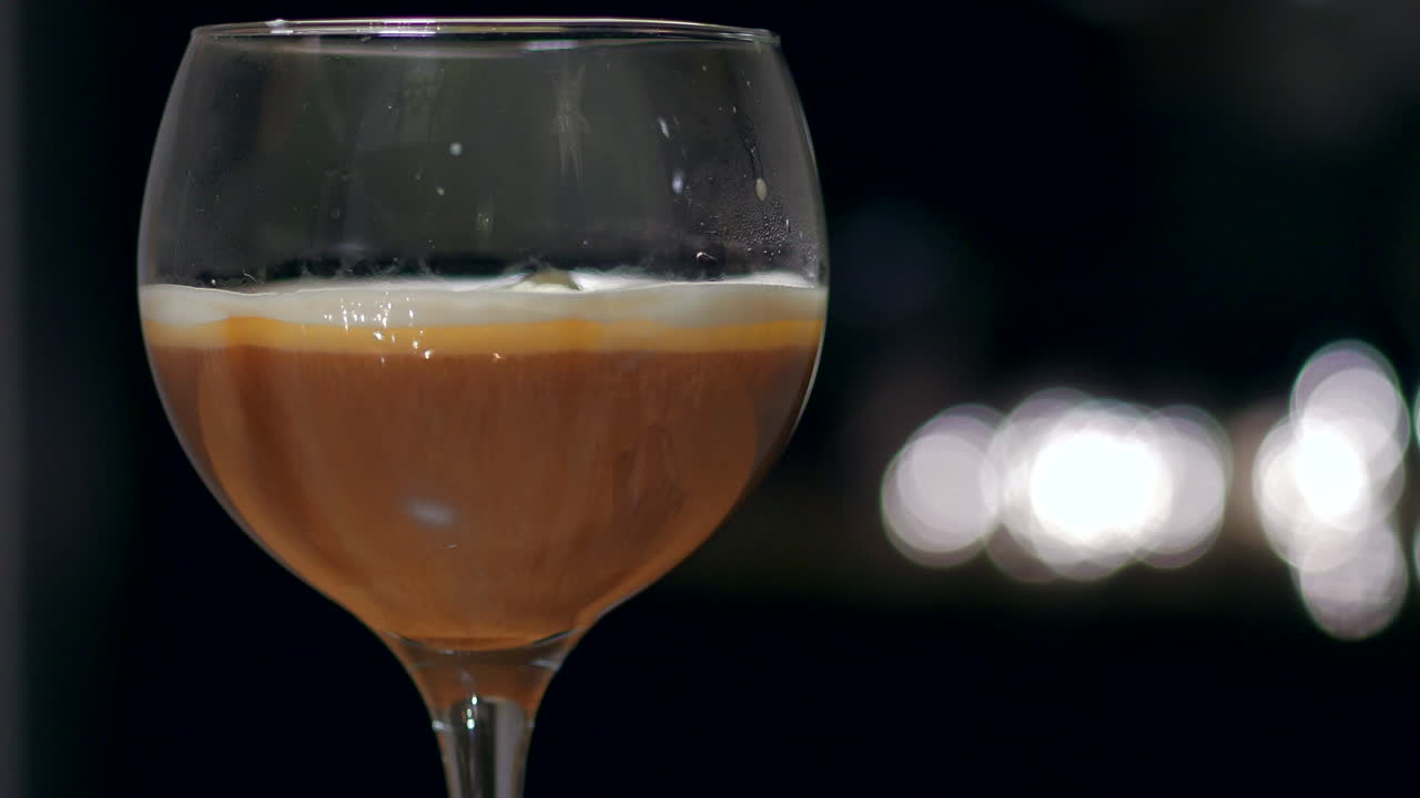 Primo piano di panna montata che cade in un bicchiere di caffè irlandese.