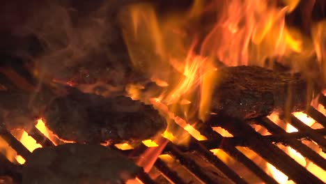 una llama a cámara lenta asando hamburguesas en una barbacoa