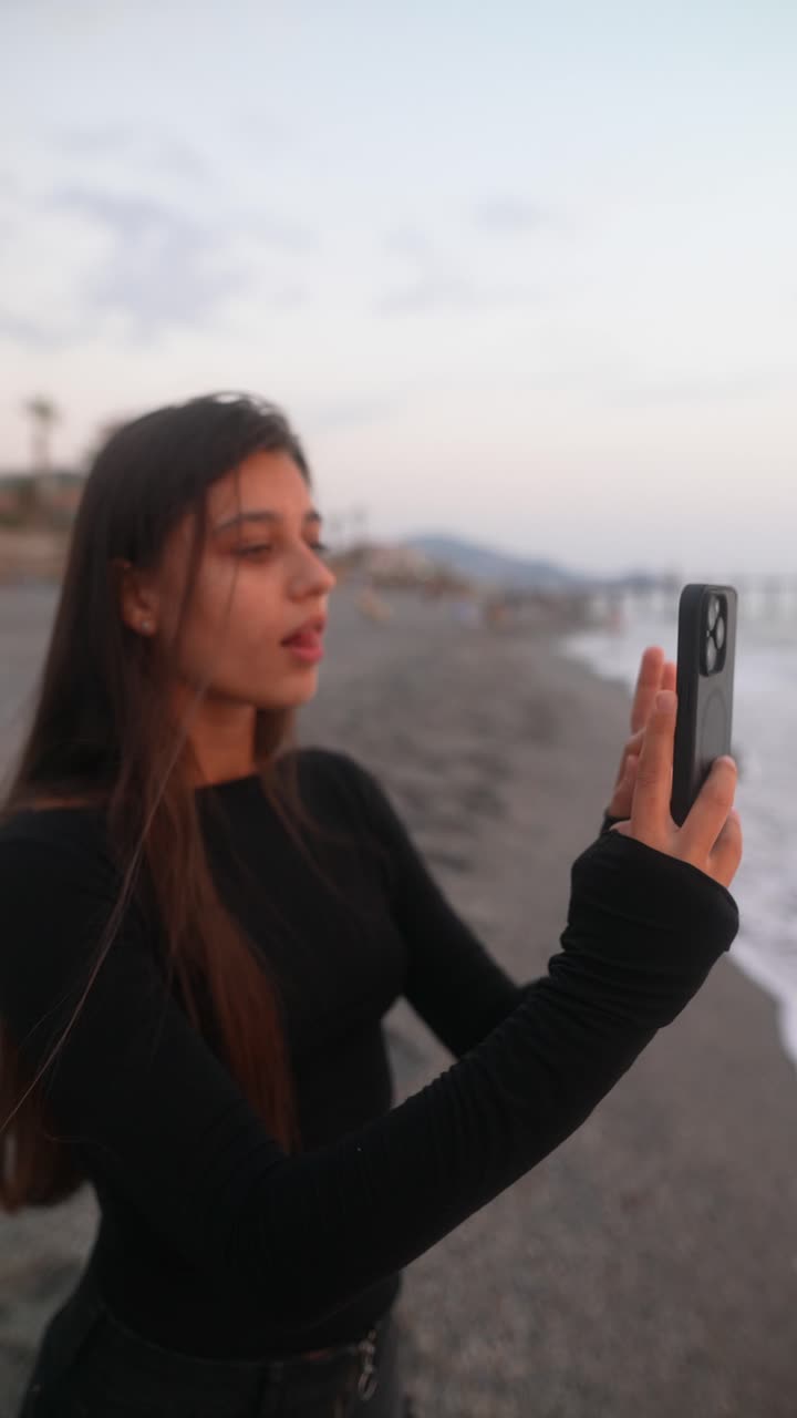 chica adolescente en la playa con un teléfono inteligente