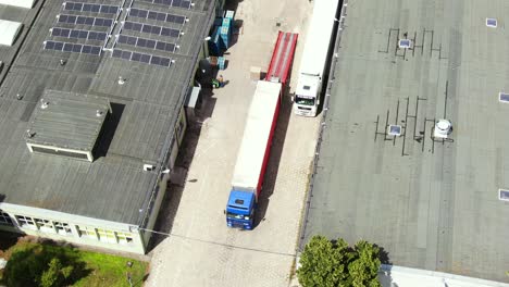 Trucks-with-semi-trailers-stand-on-the-parking-lot-of-the-logistics-park-with-loading-hub-and-wait-for-load-and-unload-goods-at-warehouse-ramps-at-sunset