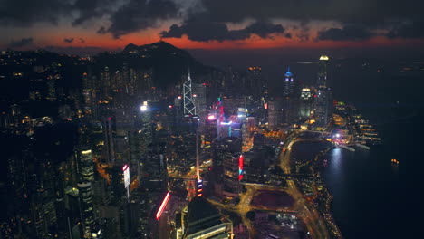 Toma-Aérea-Ultra-Ancha-De-Seguimiento-Lento-Hacia-Atrás-Del-Horizonte-Frente-Al-Puerto-De-Suspenso,-Hong-Kong,-Con-Un-Resplandor-De-Puesta-De-Sol-Cinemático-Malhumorado