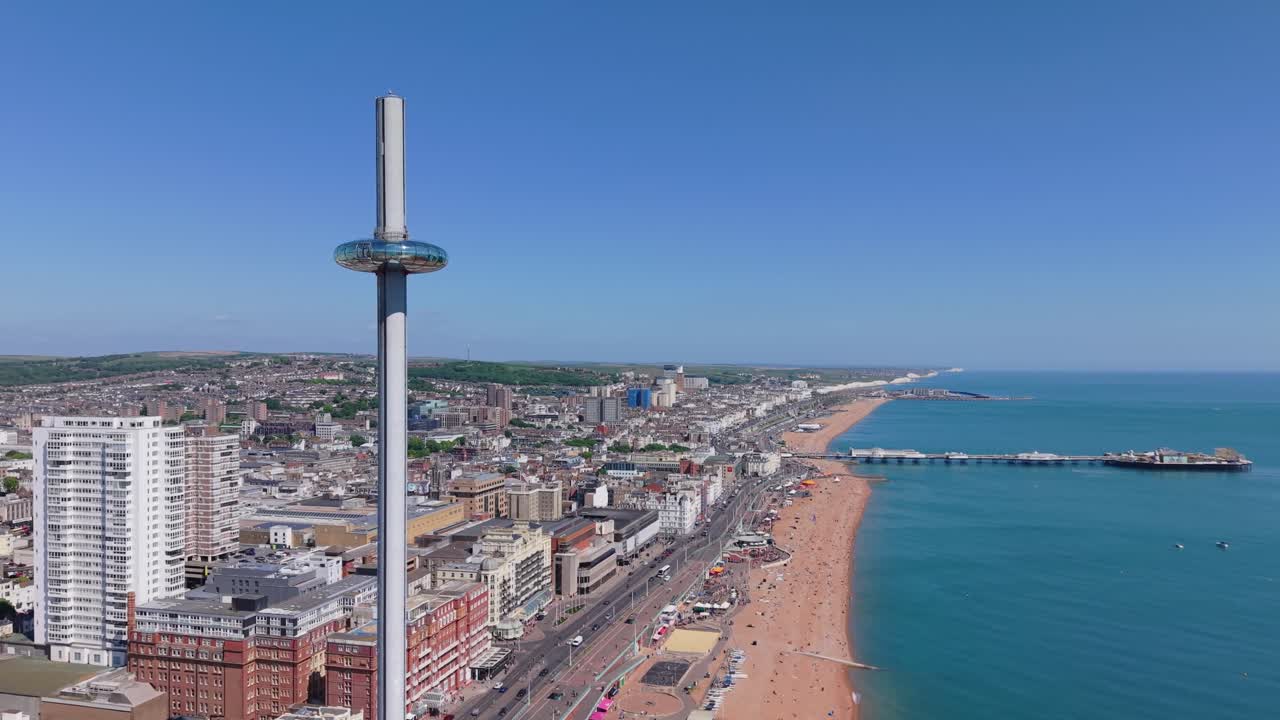 Drone orbit of the i360 Tower in Brighton on a sunny day. City life, beachgoers, and swimmers captured in vibrant coastal atmosphere