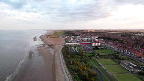 above the horizon, video footage presents the splendor of a sunset over skegness, a delightful coastal town in the uk, featuring the town, promenade, pier, and coastline