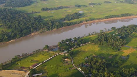 aerial view of surma river running through rural green countryside fields in sylhet, bangladesh