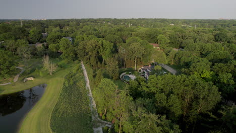 Sobrevuelo-De-Un-Estanque-Del-Parque,-árboles-Y-Casas-En-Un-Hermoso-Vecindario-En-La-Ciudad-Y-El-Campo-En-St.