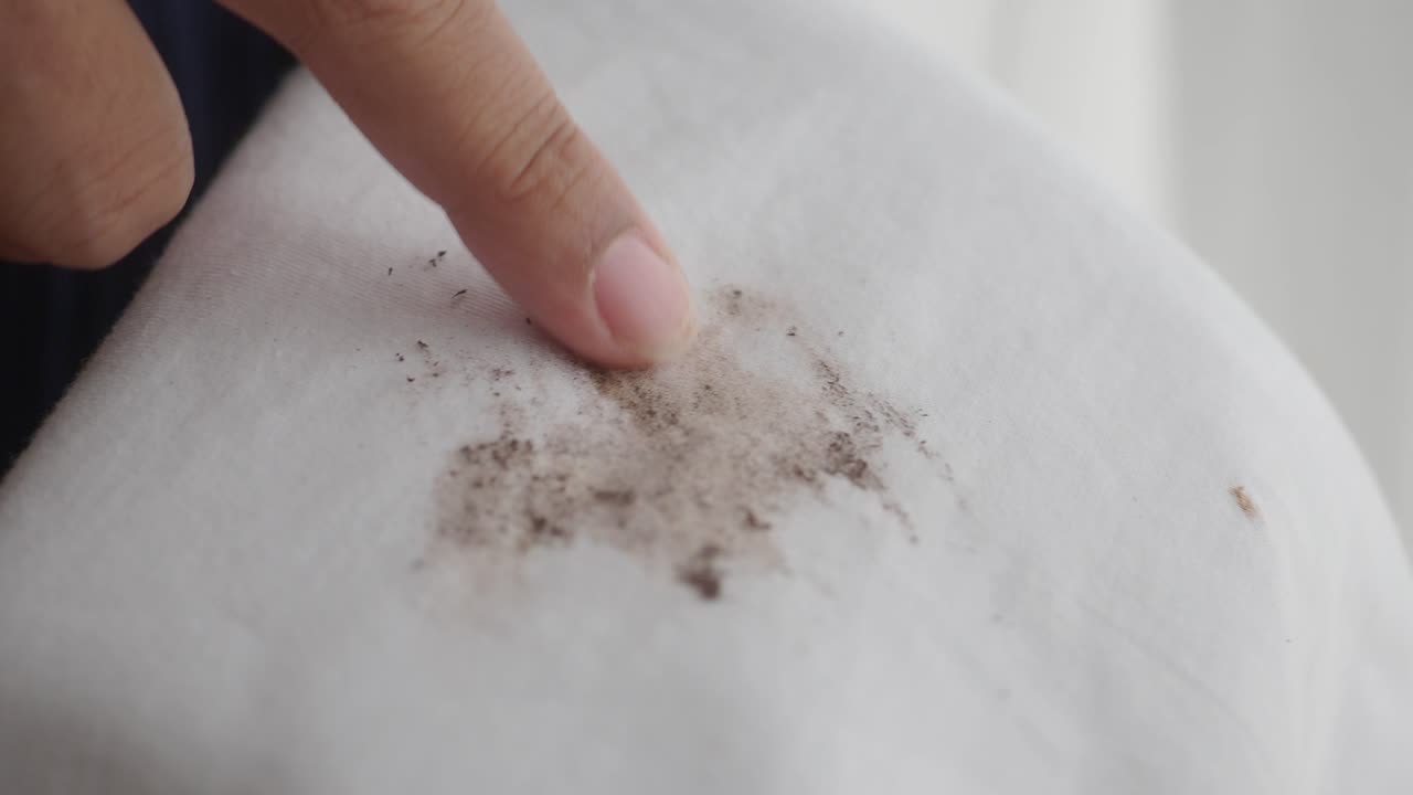 셔츠 에 있는 얼룩 을 가리키는 손가락 의 클로즈업