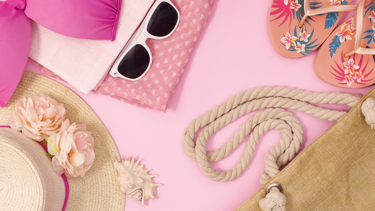 los accesorios de playa de verano se mueven uno por uno sobre un fondo rosa pastel.