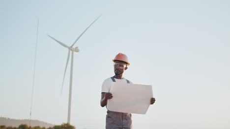 ingeniero revisando los planes de la turbina eólica al atardecer