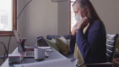 woman wearing face mask and using laptop at home