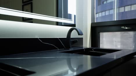 tight shot of a modern black faucet in a sink in a bathroom