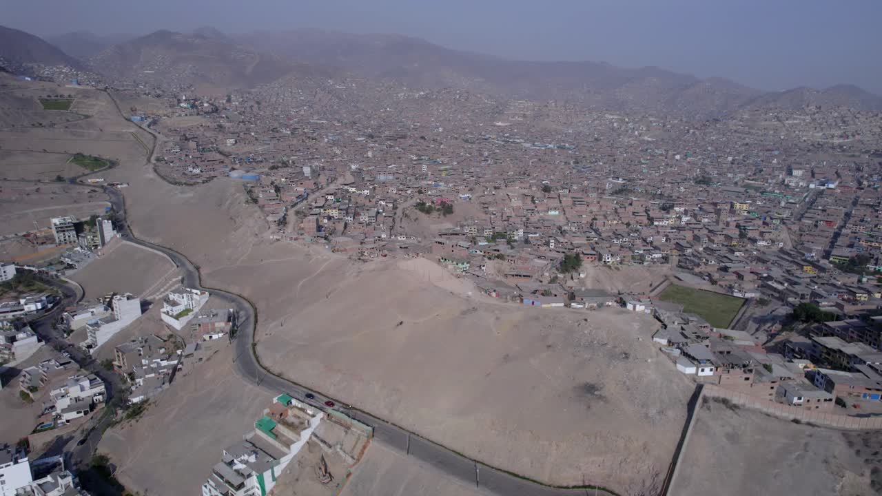 Vista aerea di un esteso insediamento informale su pendii aridi.