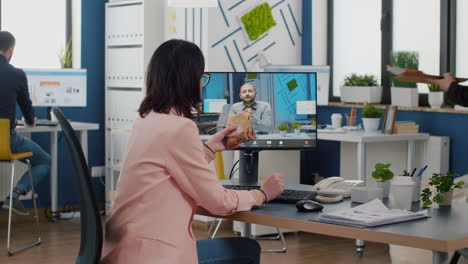 Businesswoman-sitting-at-desk-in-company-office-eating-sandwich-during-online-videocall-conference