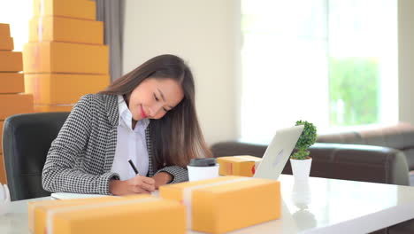 female worker online store owner using laptop at work preparing parcel boxes checking ecommerce shipping online retail e-commerce store order fulfillment in dropship delivery post office from home