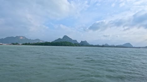 calm ocean waves and distant mountains under a partly cloudy sky, captured from a moving boat near koh samui