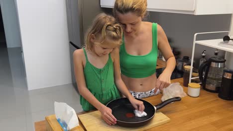madre y hija limpiando una sartén en la cocina