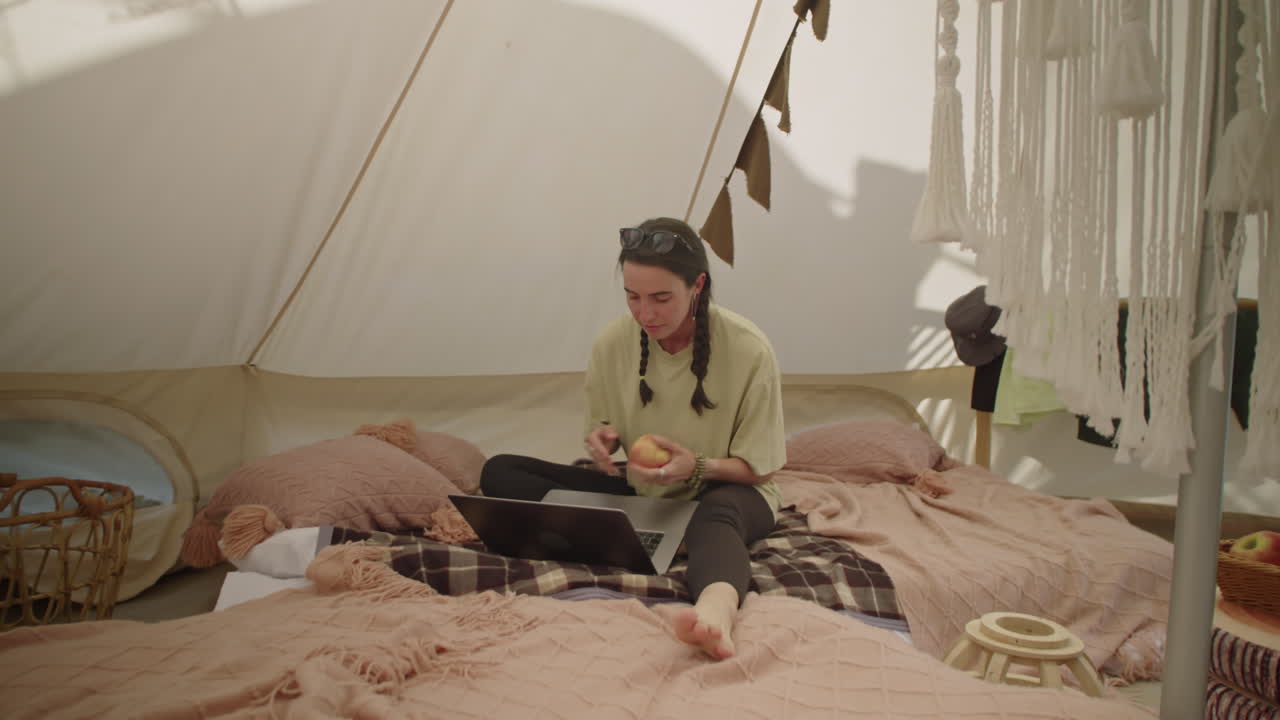 Girl Walking in Glamping Tent, Taking Apple and Using Laptop