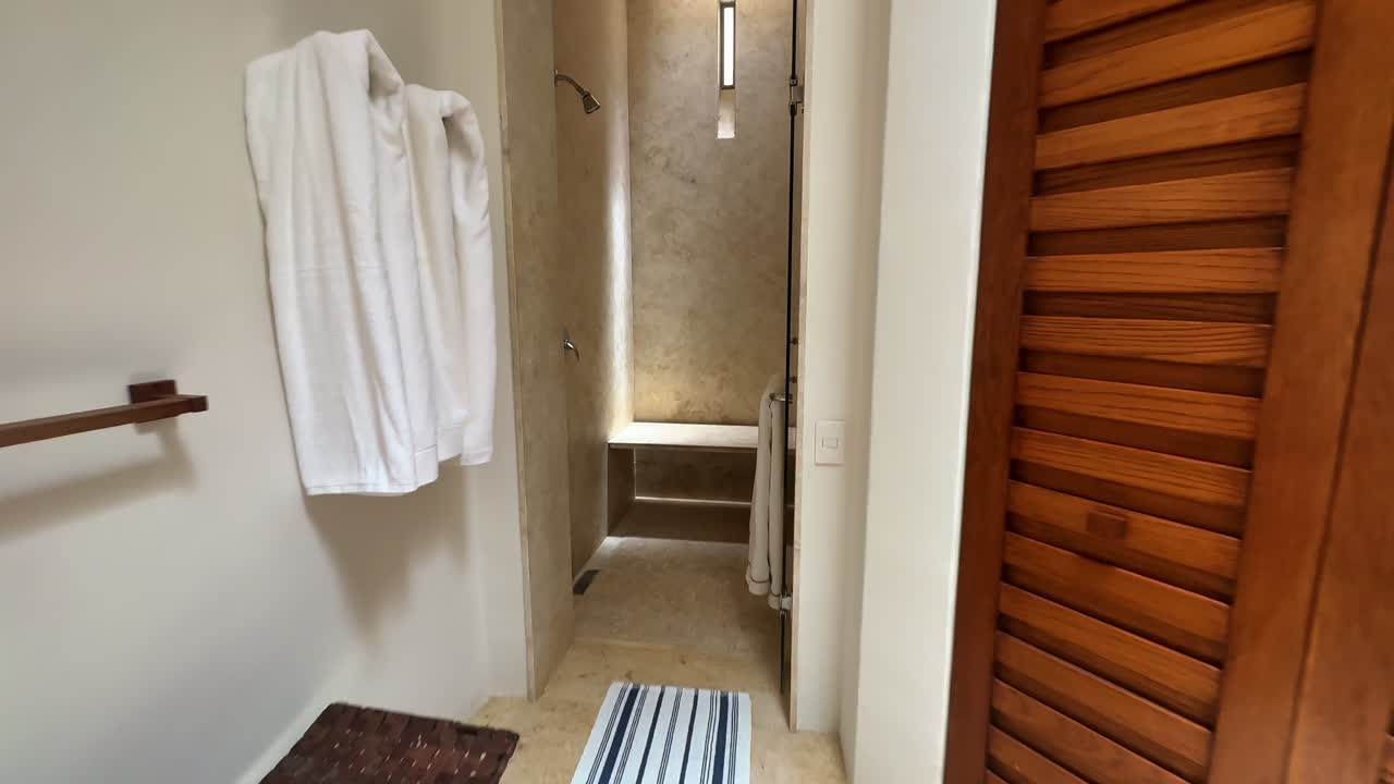 Baño luminoso con toallas, alfombra de rayas y un ambiente de ducha acogedor