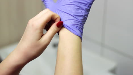 mujer caucásica se pone guantes morados para prevenir la infección por coronavirus