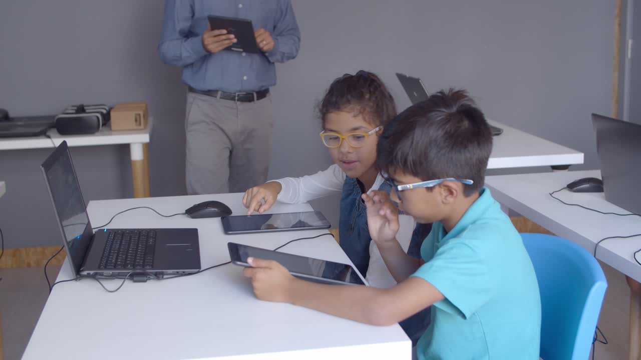 niños de escuela enfocados con gafas usando tabletas en la clase