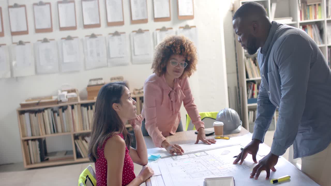 Busy diverse architects discussing blueprints on table in office, slow motion