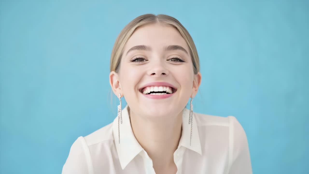 Montage of a young blonde woman wearing a white shirt and earrings, changing facial expressions, from a slight smile to a full laugh, isolated on a blue background