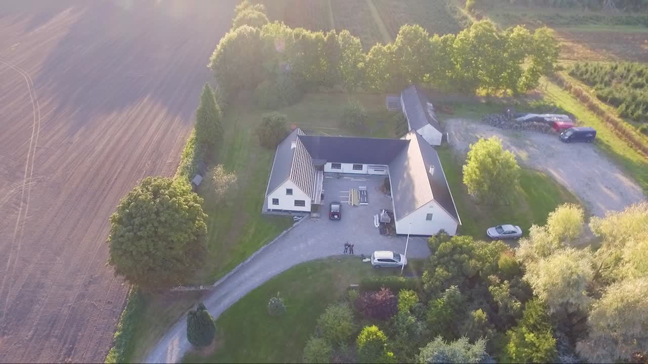 Aerial video orbit around a farm during sunset.