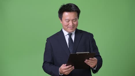 mature japanese businessman against green background