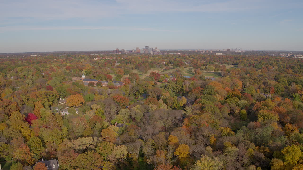 sobrevuelo de árboles de otoño con una pequeña iglesia y un horizonte de la ciudad en el horizonte