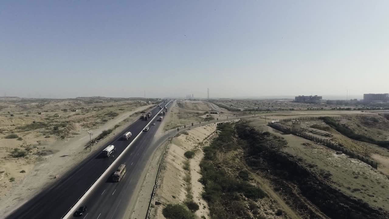 고속도로와 도시의 공중 느린 모 뷰, 무거운 트롤 어선과 자동차가 고속도로에서 움직이고 있고, 인터체인지가 연결되고 있습니다.