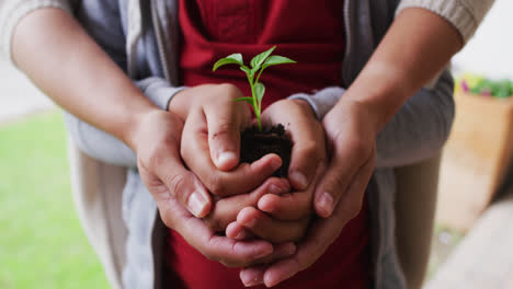 Mixed-race-mother-and-daughter-holding-a-plant