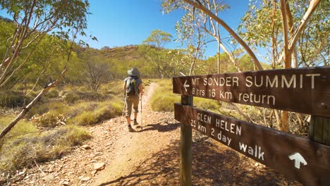 excursionista camina más allá de la señal de mt sonder en el sendero larapinta, australia central