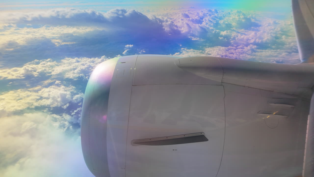 Vibrant sky view from a plane window, focusing on the jet engine and clouds illuminated by sunlight.