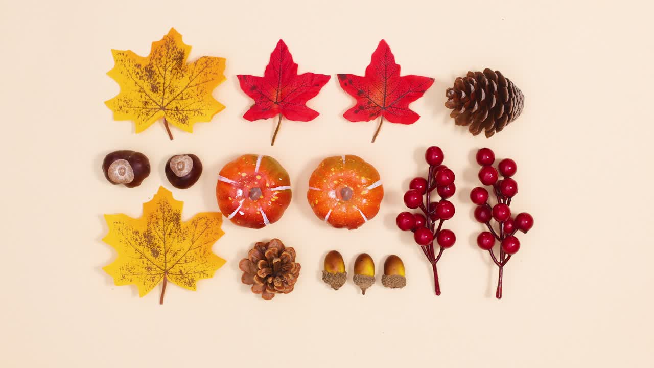 Creative autumn leaves and fruits appear and make layout on beige background. Stop motion