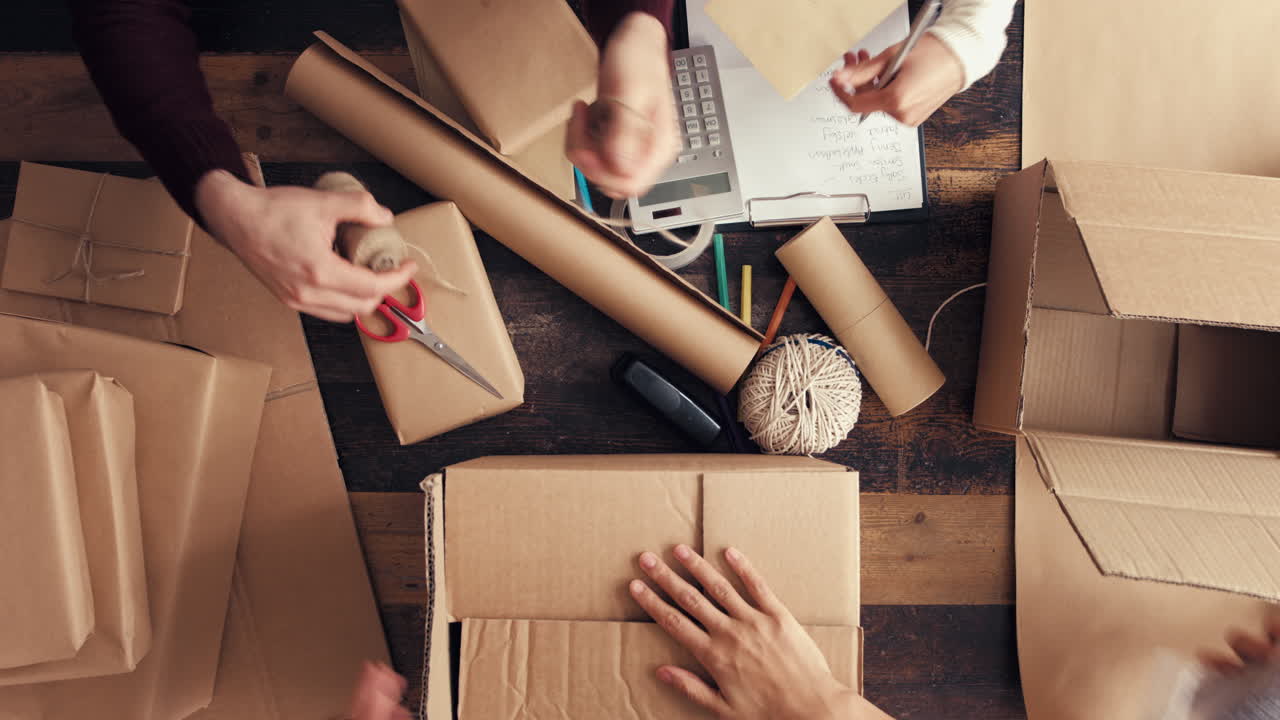 Hands wrapping packages for postage from above