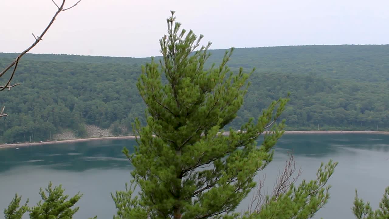 Una veduta quasi aerea di una strada in lontananza proprio accanto a un lago in una regione montuosa.