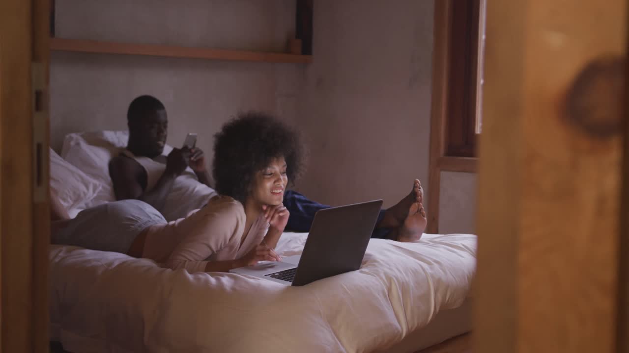 Couple on smartphone or computer in bedroom
