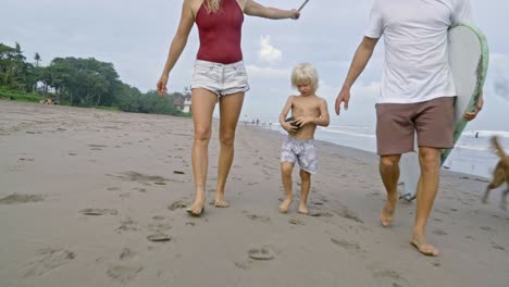 family walking on beach with dog on vacation