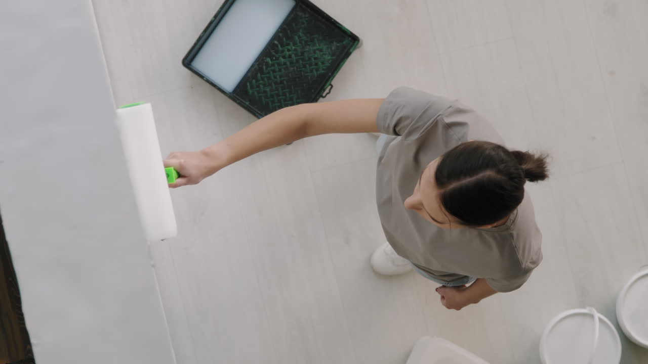 mujer pintando pared con rodillo