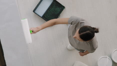 mujer pintando pared con rodillo