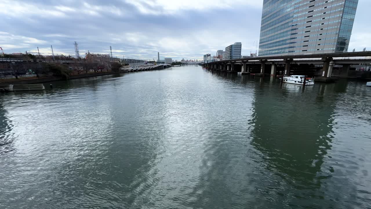A calm river view in Tokyo, Japan, with bridges and urban surroundings under cloudy skies