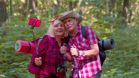una pareja de mayores tomando una selfie mientras caminan en el bosque