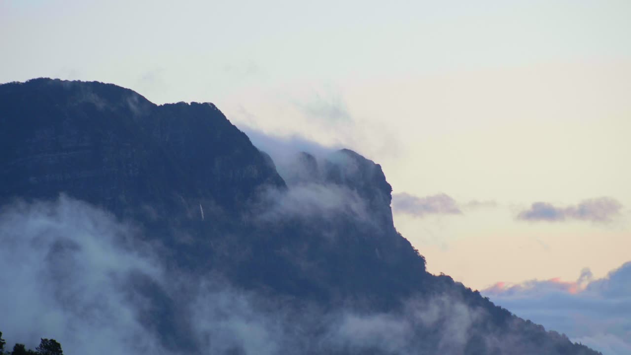 Spectacular footage capturing the mesmerizing sight of clouds gracefully gliding beneath a towering mountain, revealing nature's grandeur and dynamic beauty