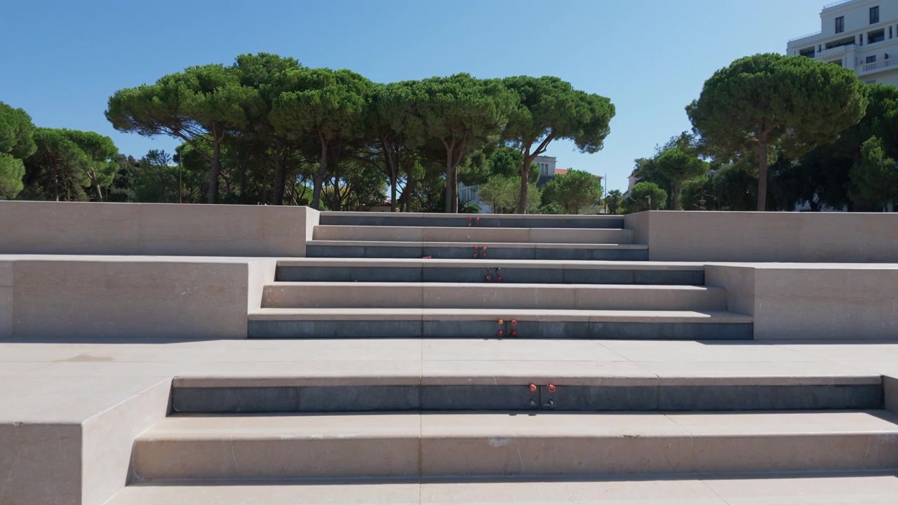Ampi gradini in pietra che salgono attraverso un parco con alti pini e un edificio bianco sullo sfondo, Juan-les-Pins, Francia